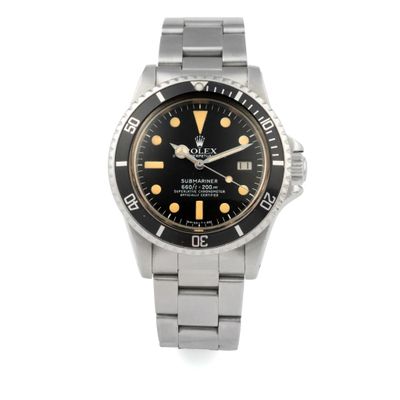 a watch with a black dial and yellow hands on a silver bracelet