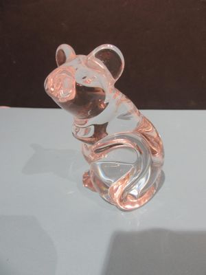 une figurine en verre représentant une souris assise sur une table