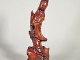 une statue en bois représentant une femme tenant un oiseau perché sur une branche