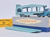 un petit bus bleu posé sur une boîte, avec une boîte jaune à côté