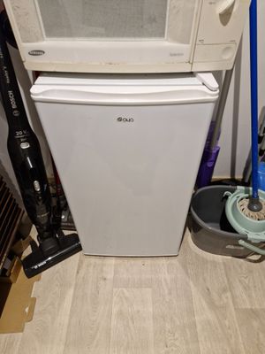 a white refrigerator and a black and white vacuum on the floor