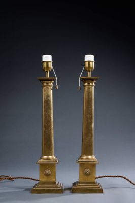 a pair of brass candles on stands with a rope