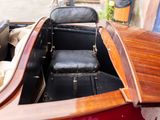 a small wooden boat sitting in the back of a red car
