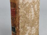 an old book sitting on top of a table next to a white wall
