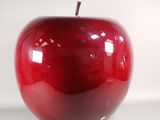 une pomme rouge posée sur une surface blanche