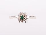 a close up of a ring with a green stone surrounded by diamonds