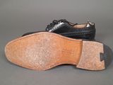 pair of men ' s black leather shoes on a grey surface