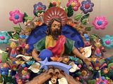 a statue of jesus sitting on top of a pile of flowers