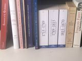Plusieurs livres sont alignés sur une étagère devant un mur noir