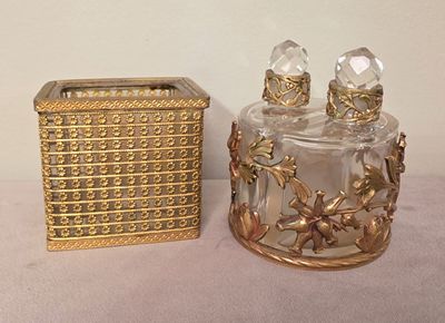 a gold box and a glass perfume bottle sitting on a table