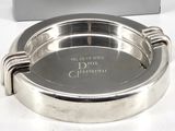 a silver ashtray on a white table with a box in the background