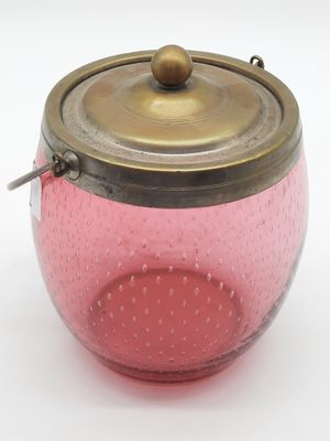 un bocal en verre rose avec un couvercle en laiton