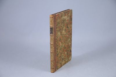 un vieux livre posé sur une table à côté d'un mur blanc