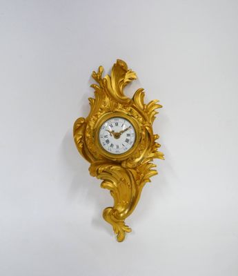 une horloge dorée accrochée au mur sur fond blanc