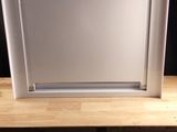 a white microwave sitting on a wooden shelf next to a cup