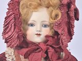 an image of a doll with red hair wearing a red dress and a red bonnet