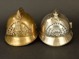 pair of silver and gold fire helmets on a black background