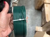 a person holding a spool of green wire in their hand