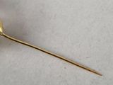 a close up of a gold plated flower on a white surface