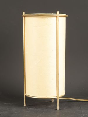 a brass table lamp with a white shade on a black background