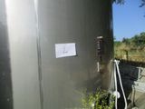 un réservoir métallique sur lequel est apposée une pancarte, à côté d'un arbre