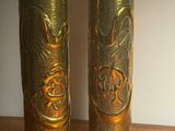 deux vases en or posés sur une table en bois, avec un mur blanc en arrière-plan