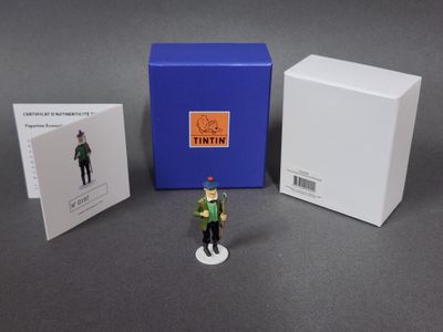 figurine représentant un homme en uniforme vert, coiffé d'un chapeau rouge et tenant une boîte bleue