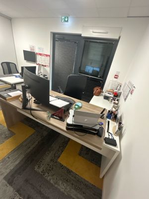 un bureau sur lequel sont posés deux écrans et un ordinateur portable