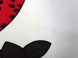 a close up of a red and black flower on a white shirt