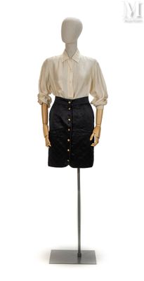 mannequin vêtu d'une chemise blanche et d'une jupe noire, posé sur un support métallique