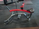 a red and silver bench in a gym with other gym equipment
