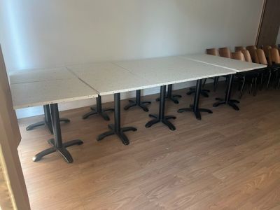 tables and chairs in a room with wooden floors and a white wall