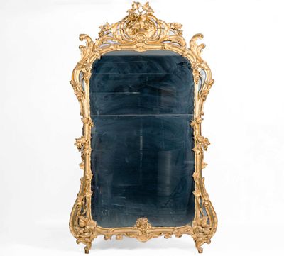 un grand miroir avec un cadre doré accroché au mur