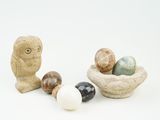 un petit oiseau perché sur un rocher à côté d'un bol d'œufs