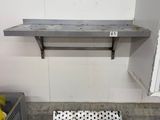 a metal shelf on the wall next to a trash can