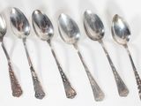 six spoons are lined up in a row on a white surface