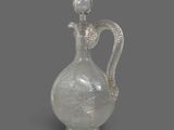 a glass bottle with a snake handle on a gray background
