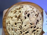 someone is holding a carved object in their hand on a table