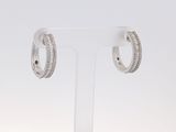 une paire de boucles d'oreilles créoles en diamant posées sur un présentoir transparent