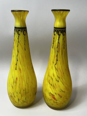 une paire de vases en verre jaune posés sur une surface blanche