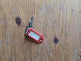 a red pocket knife on a wooden table next to a pair of scissors