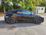 the tesla model y is parked on the street in front of a house