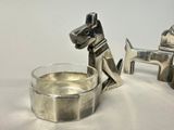 a silver dog statue next to a glass of water