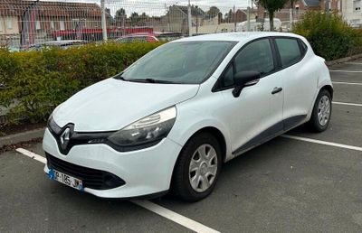 une voiture blanche garée sur un parking, à côté d'une haie