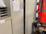 two metal lockers in a warehouse with a safety vest on top of them