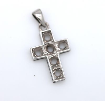 a close up of a silver cross on a white surface