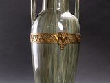 a green vase with a gold decoration on it