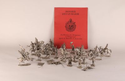 des figurines en argent représentant des soldats et un livre rouge posés sur une surface blanche