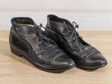 pair of black leather boots sitting on top of a wooden table