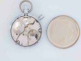 a silver pocket watch and a coin on a white surface